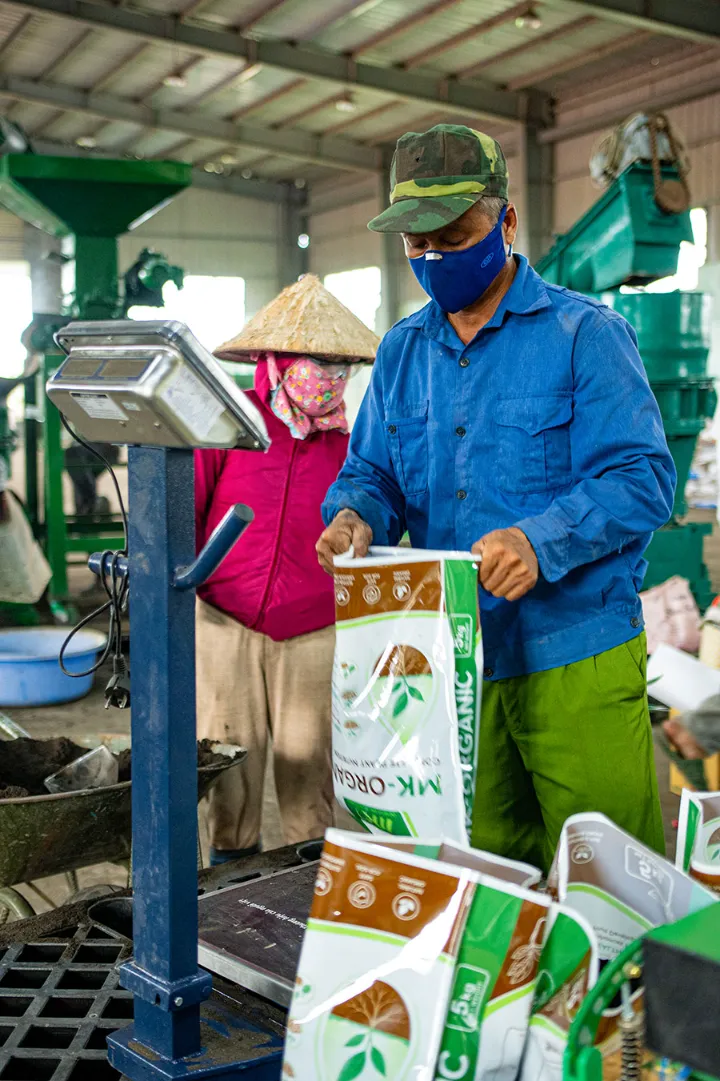 Công nhân cân và đóng bao phân bón hữu cơ dạng hạt